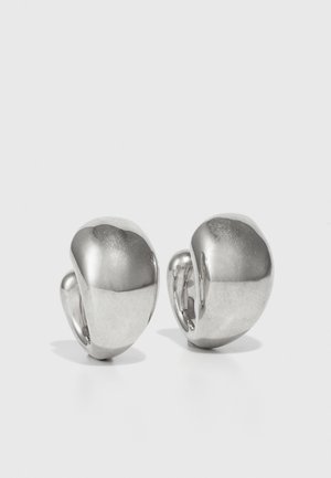 Boucles d'oreilles en métal avec une finition argentée polie, présentant une forme lisse et arrondie ainsi qu'un design sculptural élégant.