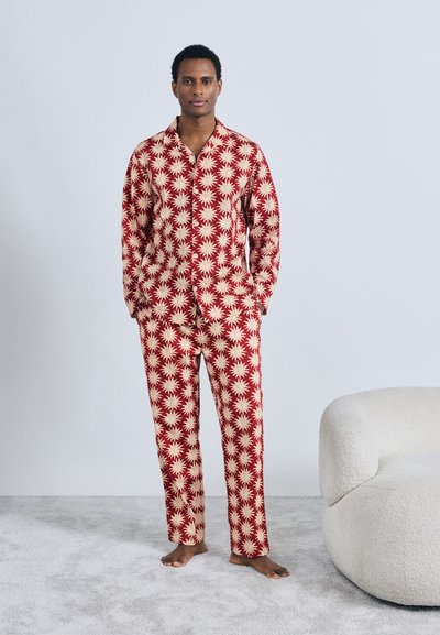 Set de pijama roșu și crem cu model de stea, compus dintr-o cămașă cu nasturi și pantaloni lungi, confecționat dintr-un material neted. Fără elemente metalice vizibile.