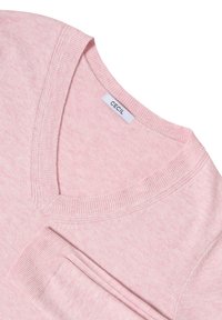 Suéter rosa claro con diseño de escote en V, con puños y dobladillo acanalados. Fabricado con material suave, la etiqueta dice "CECIL." Textura lisa, sin patrones.