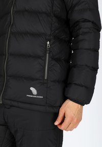 Svart puffjacka med kviltad textur, utrustad med en dragkedjeficka och "Premium Down"-logotyp i vitt. Slät material och kort längd.