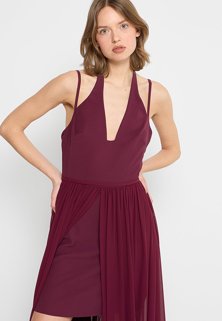 Bordeaux-Kleid mit tiefem V-Ausschnitt, dünnen Trägern und einem fließenden, plissierten Überwurf. Hergestellt aus weichem Stoff mit einer glatten Textur.