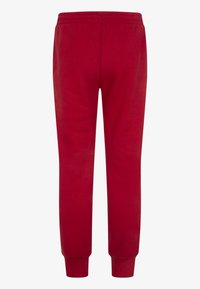 Pantalones de chándal rojos con una cinturilla elástica, puños ajustados y una textura de tela suave. Sin logotipos ni patrones visibles.