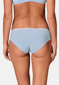 Sous-vêtements hipster bleu clair avec une texture lisse et mate et une bordure argentée contrastante le long de la taille.
