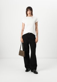 White cotton t-shirt, black wide-leg pants, black loafers, and a brown bag with zigzag accents. Minimalist design on a plain background.