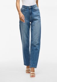 Jean taille haute à jambe droite en denim bleu moyen, avec poches avant, fermeture à bouton et décoloration subtile sur tout le tissu.