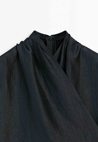 Sort kjole med høj krave og lynlås bagpå, med forside i omslagsstil og synlig stofstruktur.