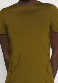 Camiseta deportiva verde de manga corta hecha de una tela suave y liviana. Presenta un logo negro de Nike en el pecho y costuras planas para mayor comodidad.