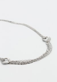 Silver kedja halsband med en texturerad, vävd design med länkade segment och en slät rund krok för fastsättning.