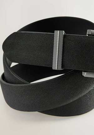 Mustan tekstuurin vyö, jossa on sileä pinta, varustettuna metallisella soljella, jossa on ruudukkomuotoilu lisäämässä otetta ja turvallista kiinnitystä.