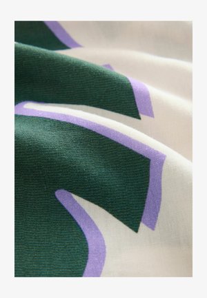 Tela verde y crema con acentos morados que presenta un diseño abstracto y audaz. La textura es suave y ligeramente arrugada.