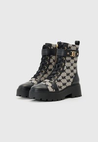 Stivaletti alla caviglia neri e beige con lacci, motivo a monogramma, suola in gomma spessa e dettagli in hardware dorato. Fondi in pelle nera liscia.