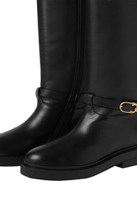 Botas de cuero negro con un acabado suave, que cuentan con una cremallera lateral, una correa texturizada con un hebilla dorada y una suela de goma baja.