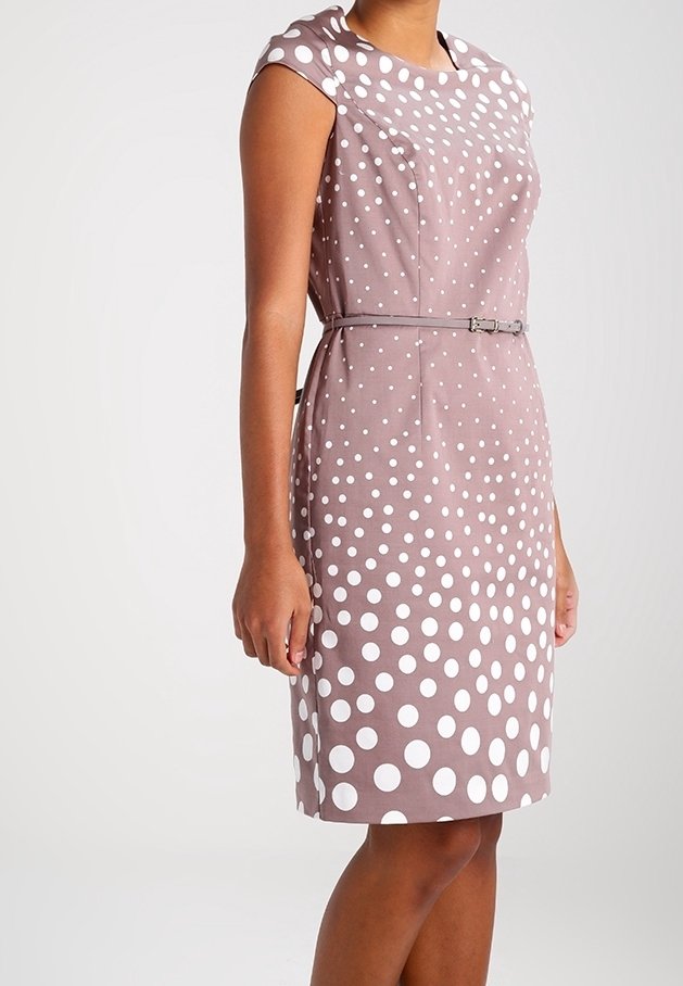 Robe mauve sans manches longueur genou à pois blancs, taille cintrée avec une fine ceinture, portée par une personne debout sur fond uni.