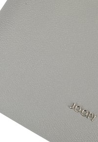 Portafoglio in pelle grigia texturizzata con logo "JOOP!" in rilievo di colore argento. Caratterizzato da un design minimalista e una superficie liscia.