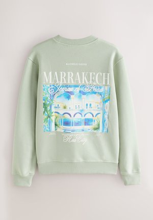 Mátově zelená mikina s kulatým výstřihem, zdobená barevným grafickým potiskem zahrady Majorelle v Marrákeši a textovými detaily.