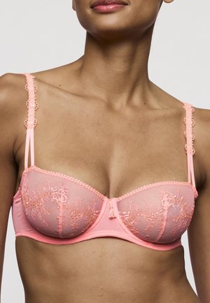 Perzikkleurige beha met kanten details, doorschijnende cups en bloemrijke borduursels. Verstelbare bandjes en haaksluiting aan de achterkant. Zachte textuur.