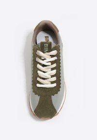 Zapatilla gris con acentos de ante verde oliva, superposiciones en forma de olas y cordones beige. Presenta una suela de goma y un interior texturizado.