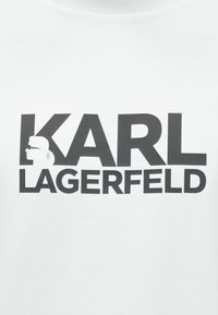 Λευκό βαμβακερό μπλουζάκι με μεγάλο μαύρο γραφικό κείμενο που γράφει "KARL LAGERFELD" με ένα σιλουέτα εικονίδιο στη αριστερή πλευρά.