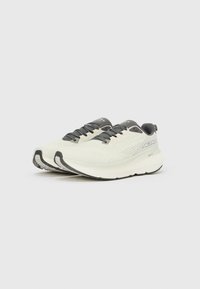 Αθλητικά παπούτσια σε ανοιχτό μπεζ με σκούρες γκρι λεπτομέρειες. Διαθέτουν επάνω μέρος από πλέγμα, επενδυμένο γιακά και υφασμένο καουτσούκ σόλα.