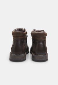 Stivaletti in pelle marrone con colletto imbottito, cerniere laterali e fodera testurizzata; suole in gomma con dettagli di cucitura a contrasto.