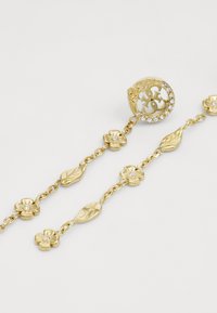 Bracciale dorato con motivi floreali e foglie, impreziosito da cristalli trasparenti. Catena regolabile con dettagli di design intricati.