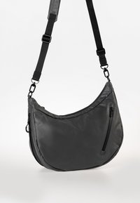 Borsa a tracolla nera realizzata in materiale liscio e resistente all'acqua. Presenta una forma curva, una tracolla regolabile e una tasca frontale con zip.