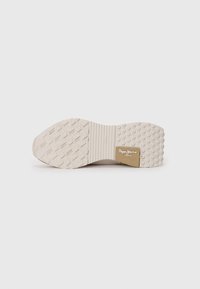 Light beige sneaker sole with textured rubber pattern, featuring a ridged area and embossed logo in gold on the side.