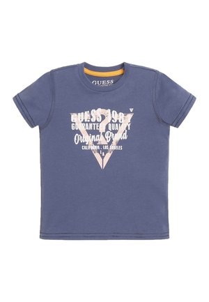 Blå Guess t-shirt med korte ærmer, rund hals og hvid tekst med teksten "Guess 1981 Guaranteed Quality Original Brand California Los Angeles"