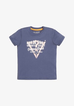 Blå Guess t-shirt med korte ærmer, rund hals og hvid tekst med teksten "Guess 1981 Guaranteed Quality Original Brand California Los Angeles"