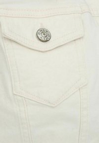 Gros plan d'une poche en denim blanc avec rabat fermé par un bouton argenté gravé du mot « ONLY ».