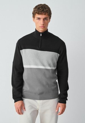 Sort og grå lynlånsweater med et farveblokdesign og en vandret lys grå stribe, lavet af blødt stof, med teksturerede ribbede manchetter.
