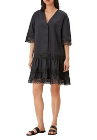 Černé bavlněné šaty s výstřihem do V, krátkými rukávy a krajkovým lemováním na spodním okraji. Mají vrstevnatý design s texturovanými akcenty.
