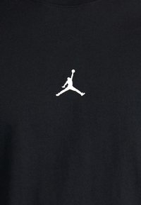 Must musta T-särk, millel on rinnal valge "Jumpman" logo. Ümmargune kaelus, sile tekstuur. Lihtne ja klassikaline stiil.