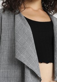 Šedý a černý károvaný blazer s volným předním dílem a texturovanou látkou, zkombinovaný s přiléhavým černým crop topem.