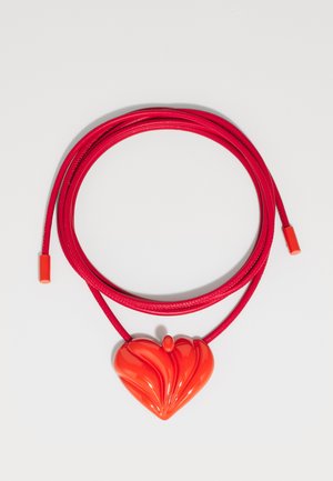 Collar rojo con un colgante en forma de corazón brillante que presenta patrones ondulados, sobre un cordón rojo suave con extremos ajustables.