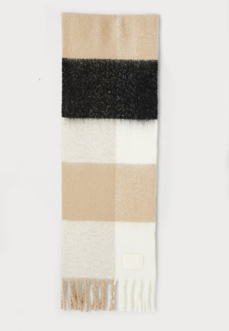 Et rektangulært, mønstrede skjerf med vekslende blokker av beige, krem og svart, med frynser nederst og et lite merke på siden.
