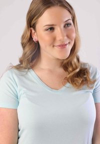 Lichtblauwe V-hals t-shirt van zachte stof, met korte mouwen en een relaxte pasvorm. Haar in losse golven, zonder opvallende patronen of accenten.