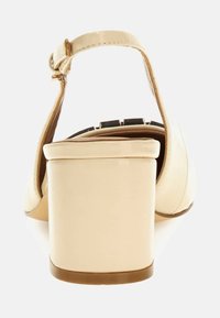 Scarpa chiusa beige con tacco quadrato, dotata di cinturino alla caviglia regolabile e una finitura liscia e lucida. Design semplice e lineare.