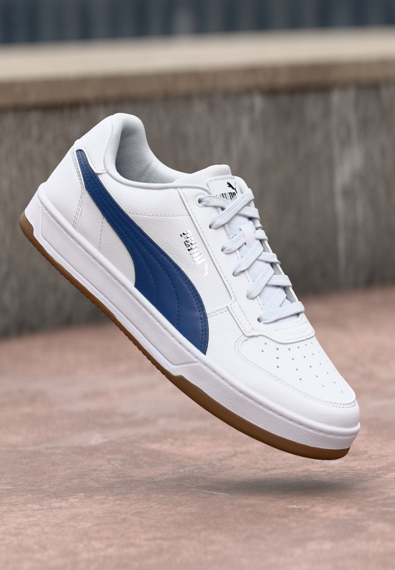 Bijela tenisica s plavom PUMA prugom, teksturirani kožni gornji dio, ravne vezice i perforirani detalji na nožnom prstu; guma potplat.