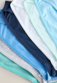 Pile de sous-vêtements en coton dans différentes couleurs pastel et bleu marine, chacun avec un bord festonné le long des bords.