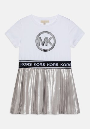 Hvid kortærmet kjole med sølv MK-logo på brystet, sort taljebånd med gentaget "KORS" tekst og metalisk plisseret sølvskørt.