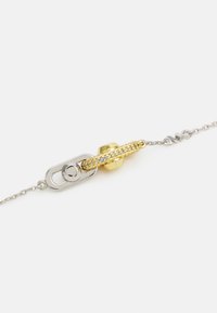 Bracciale in argento con un accento centrale in oro dalla superficie texture e pietre trasparenti, chiuso da un sistema di chiusura unico.