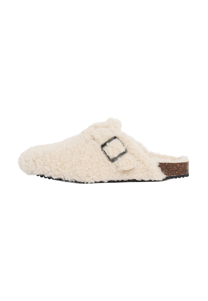 Zoccolo beige morbido con fibbia nera e suola in sughero, visto di lato su uno sfondo bianco.