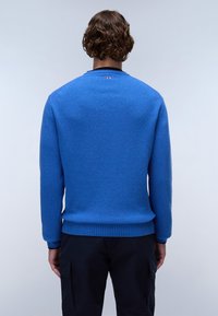 Blå stickad tröja med långa ärmar och ribbat fåll. Har en rund halsringning och en liten logotyp på baksidan nära kragen.