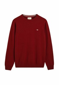 Roter Strickpullover mit rundem Halsausschnitt, gerippten Bündchen und Saum. Besitzt ein kleines gesticktes Logo auf der linken Brust. Glatte Textur.