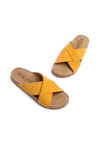 Gelbe Wildleder-Slippers mit überkreuzten Riemen, ausgestattet mit einer strukturierten Innensohle und einer leichten braunen Gummisohle.