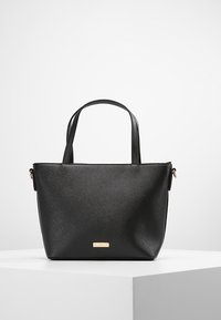 Sort tote taske lavet af tekstureret syntetisk materiale med to korte håndtag og en guld hardware detalje foran.