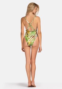 Jednoczęściowy strój kąpielowy w intensywnym zielonym kolorze z tropikalnym wzorem liści. Posiada skrzyżowane regulowane ramiączka oraz wysoki krój nogawki.