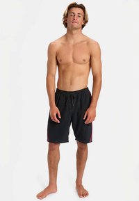 Černé plavecké šortky s kontrastními červenými proužky po stranách, elastickým pasem a šňůrkou. Materiál působí lehce a rychleschnoucí.