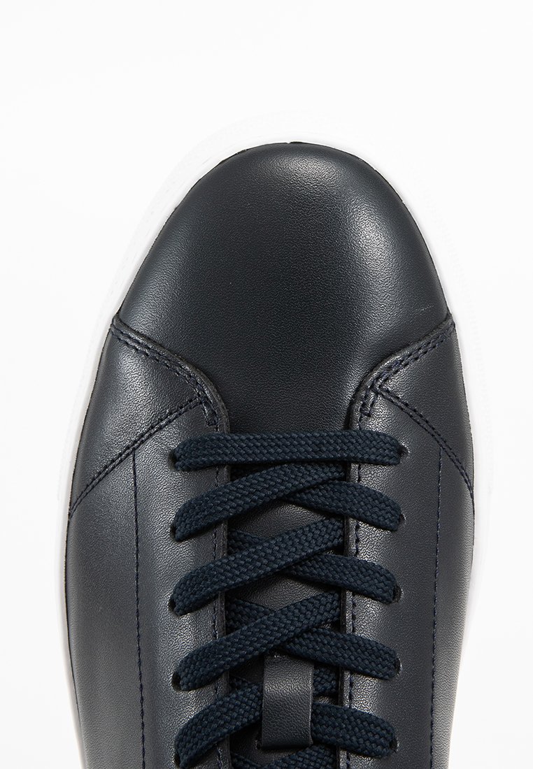 Sneaker in pelle blu navy con punta arrotondata, lacci piatti e suola in gomma bianca. Texture liscia con dettagli di cucitura discreti.